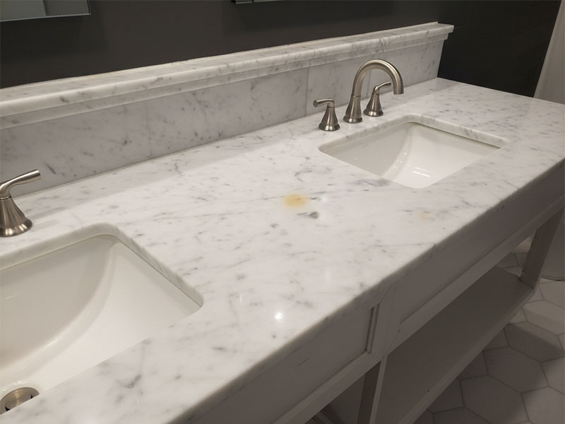 White marble vanity with small yellow stain visible on surface White marble vanity with small yellow stain visible on surface